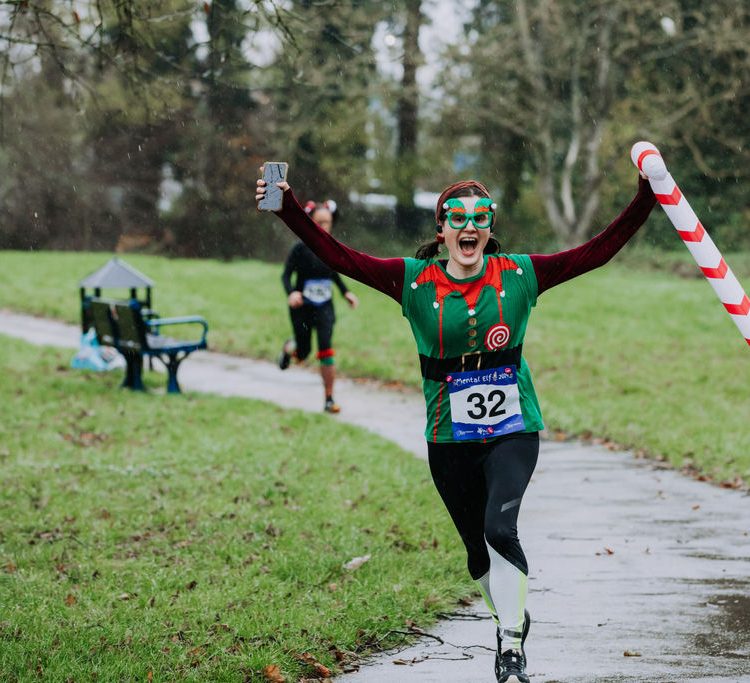 Young woman holds up an inflatable candy cane as she runs past