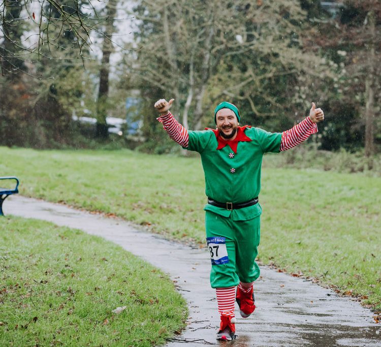 Man smiling and raising both arms in the air as he runs towards the camera