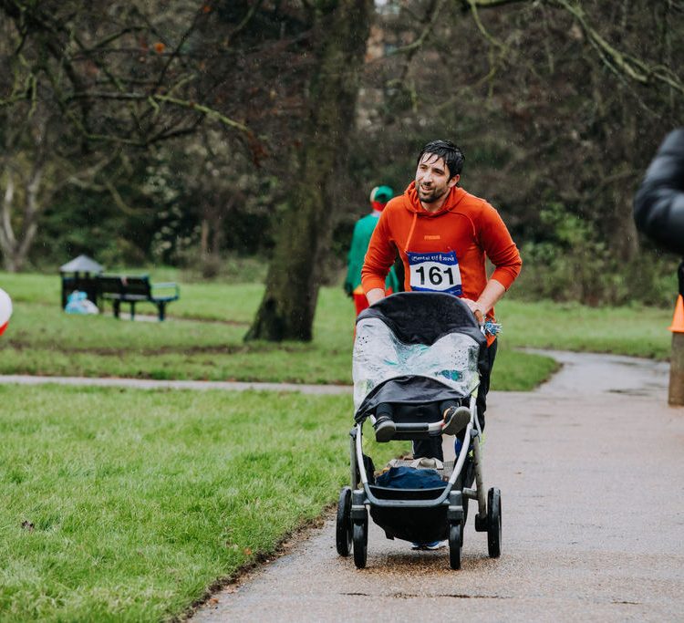 Man pushing a stroller in the rain