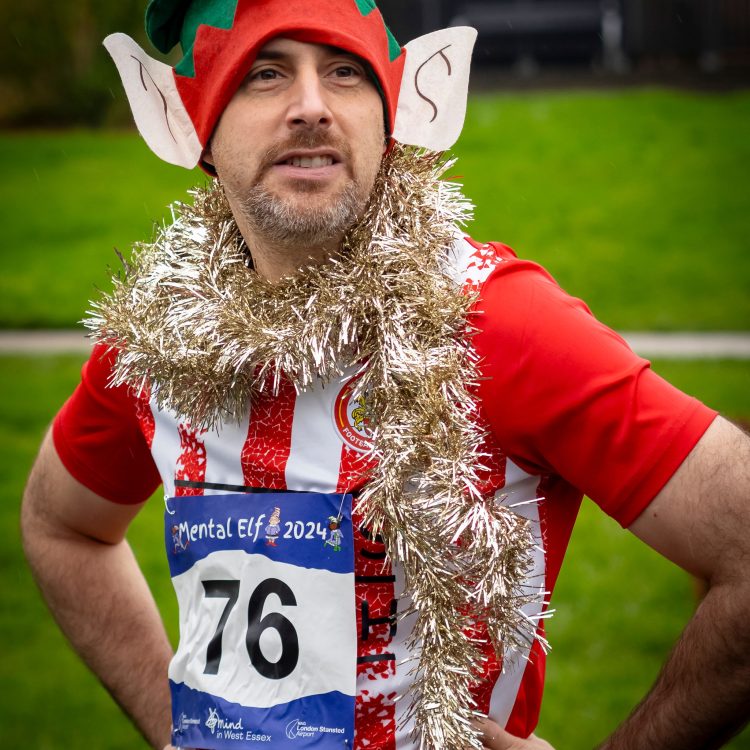 Portrait shot of man wearing an elf hat with gold tinsel draped over him