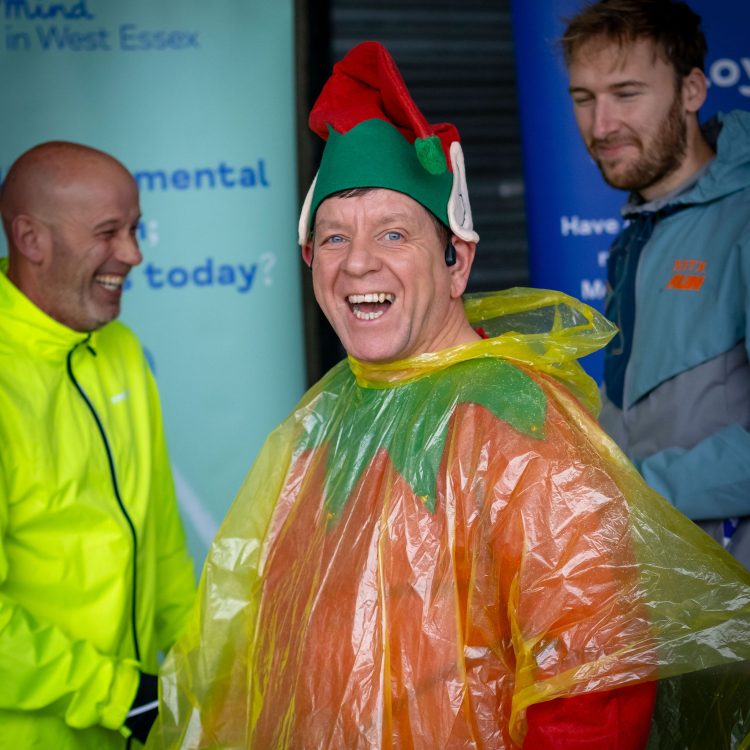 Laughing man wearing a rain poncho over his elf outfit