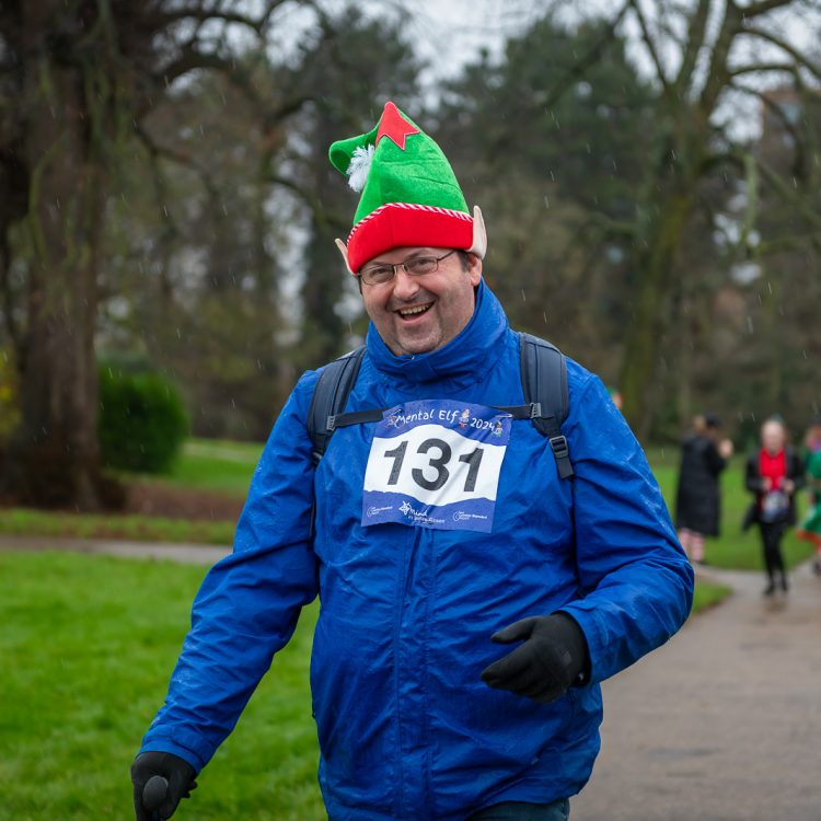 A man wearing an elf hat and rain jacket smiling