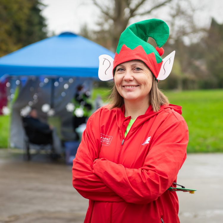Woman in an elf hat smiling with her arms crossed