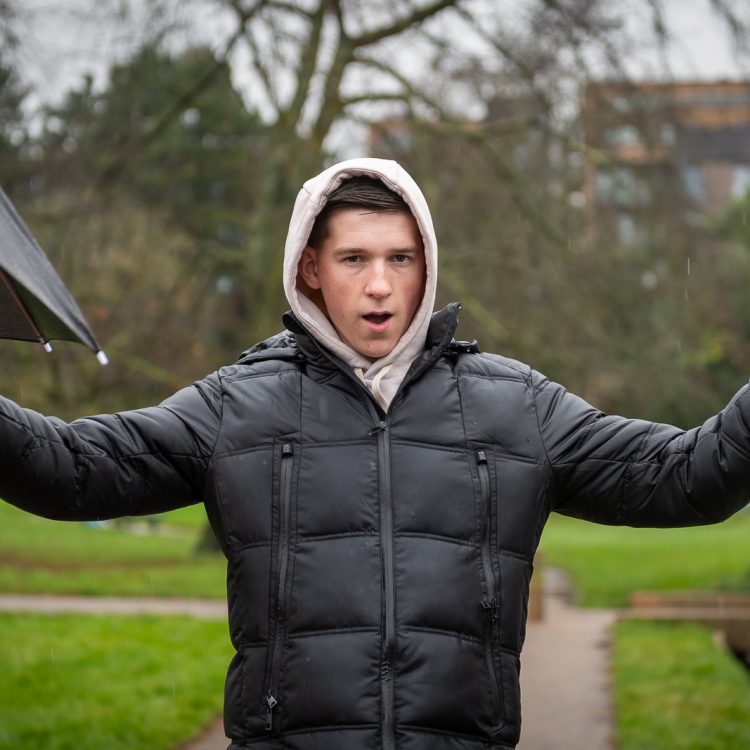 A man in a black jacket with a white hoody over his head looking at the camera