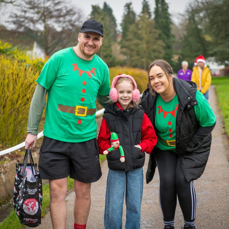 A man, woman and girl in elf-themed outfits smiling