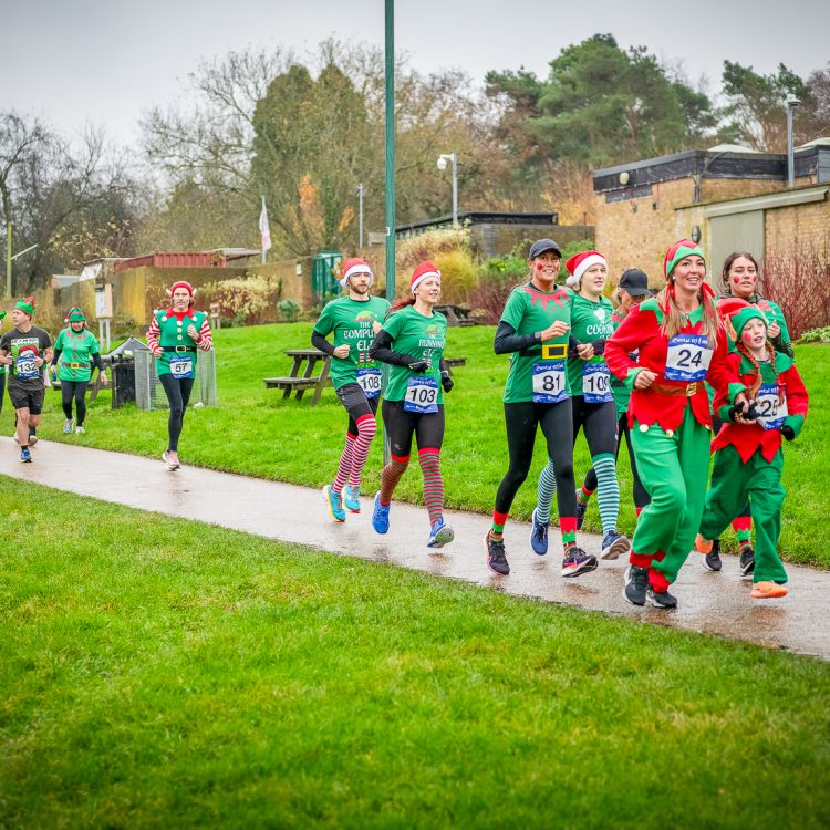 A large group of men, women and children running in colourful elf costumes