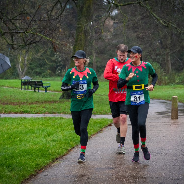 Three people in elf outfits running together