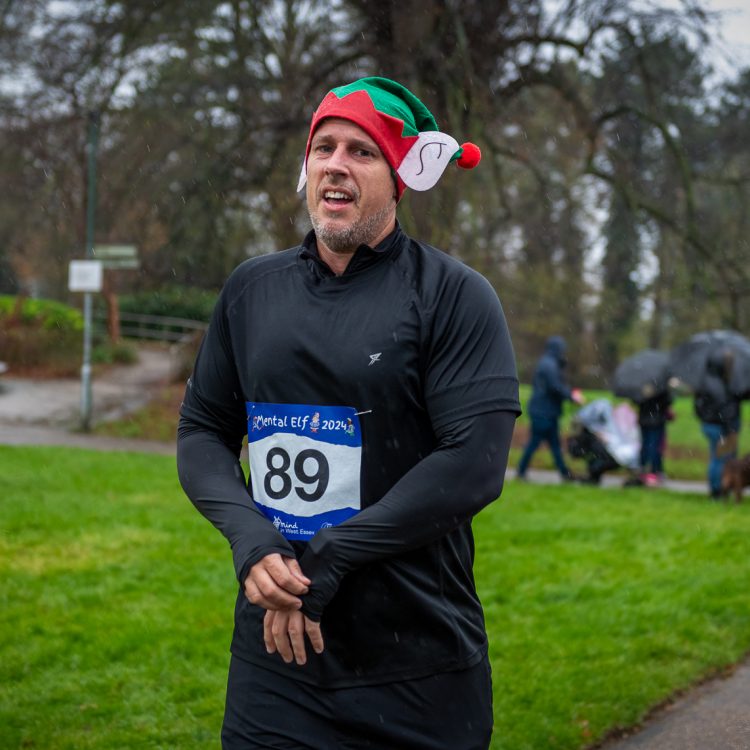 A man in an elf hat glancing at the camera as he finishes his run