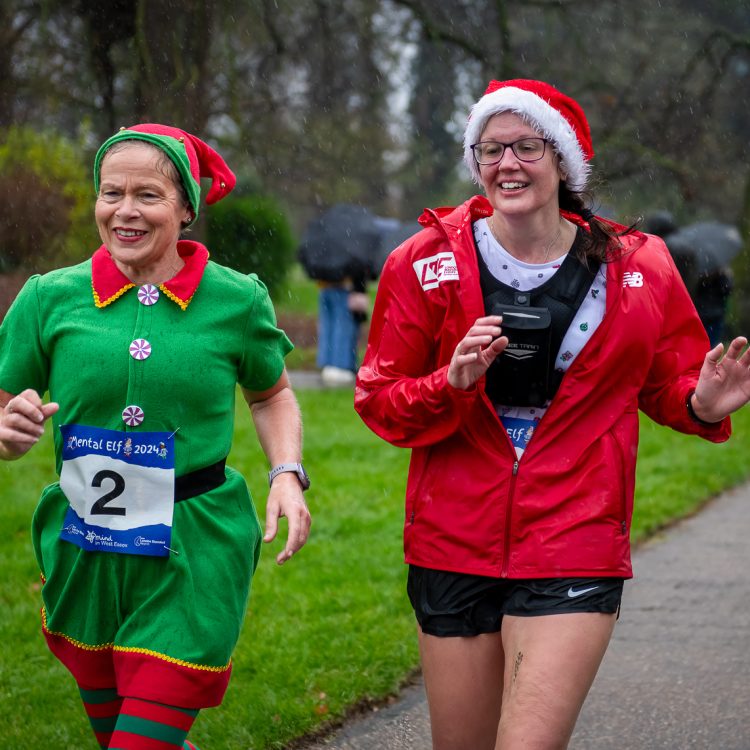 Two smiling woman running together in festive outfits