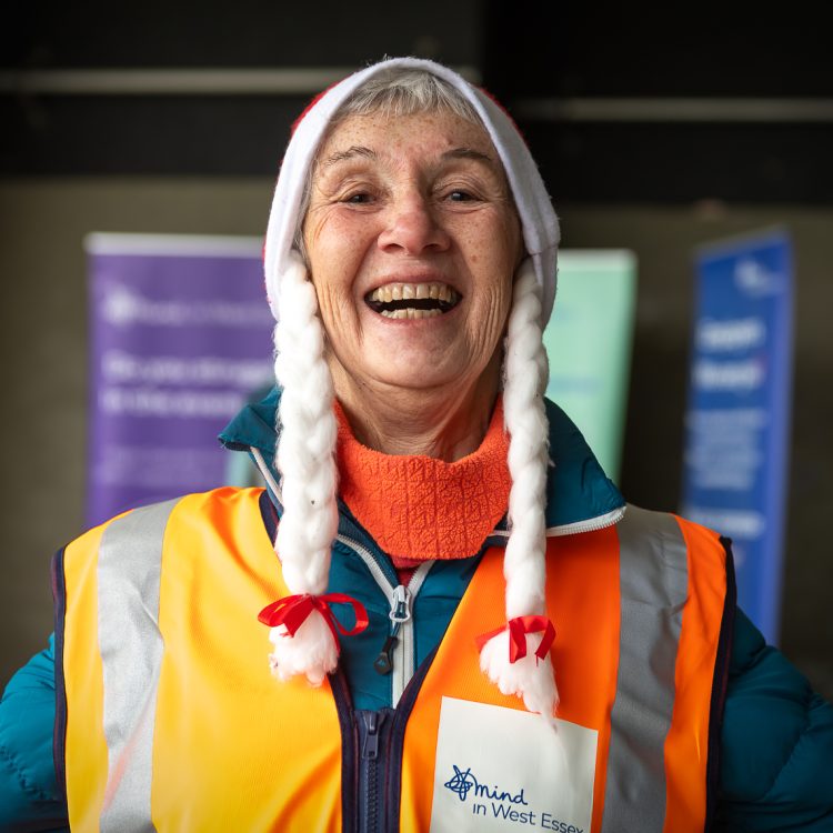 A woman in a high-vis jacket and Santa hat smiles widely at the camera