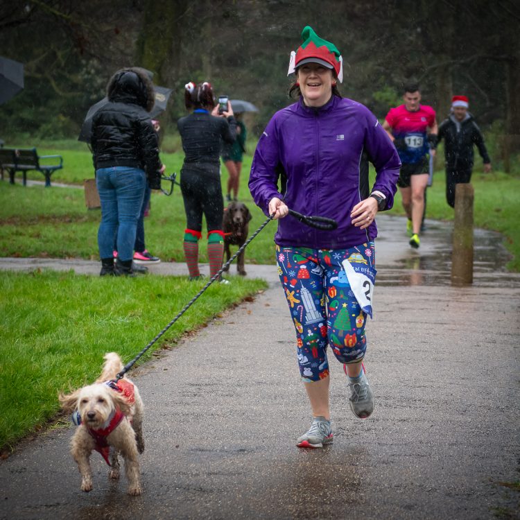 A woman in a colourful outfit jogging with her dog on a lead