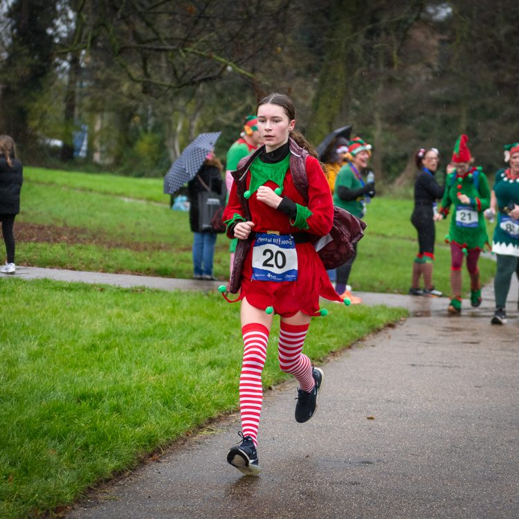 Young woman in elf outfit jogging along as others follow behind