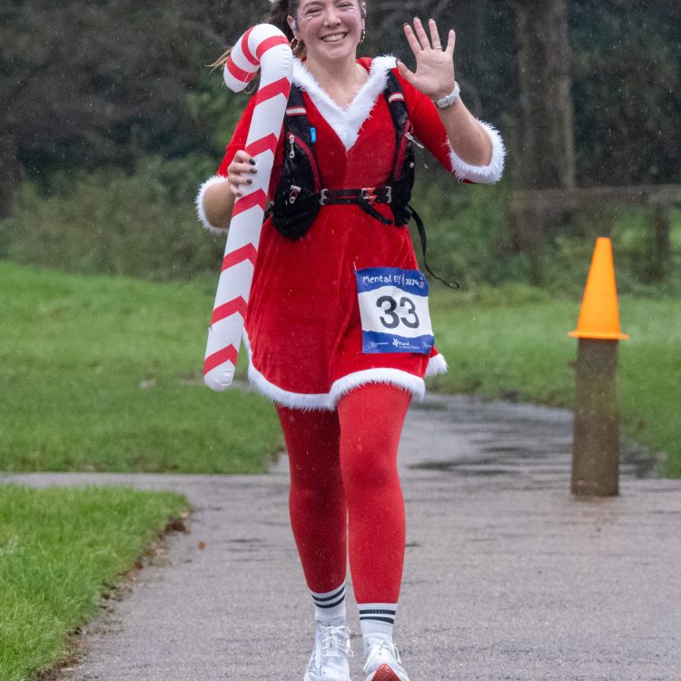 A young woman in Christmas fancy dress smiling and waving