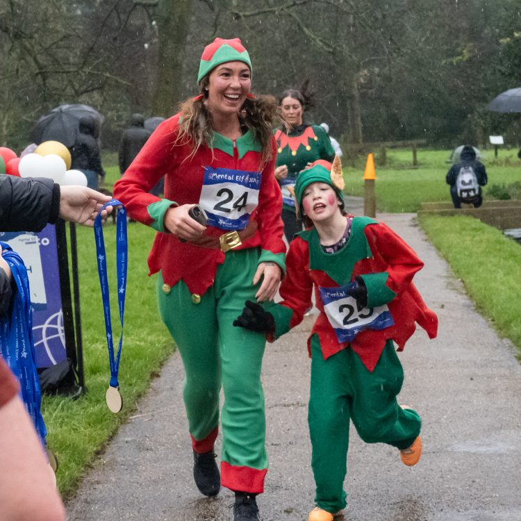 A woman and child in matching elf outfits crossing the finish line