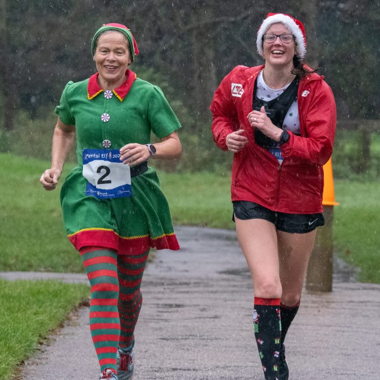 Two women in festive fancy dress running towards the camera in the rain
