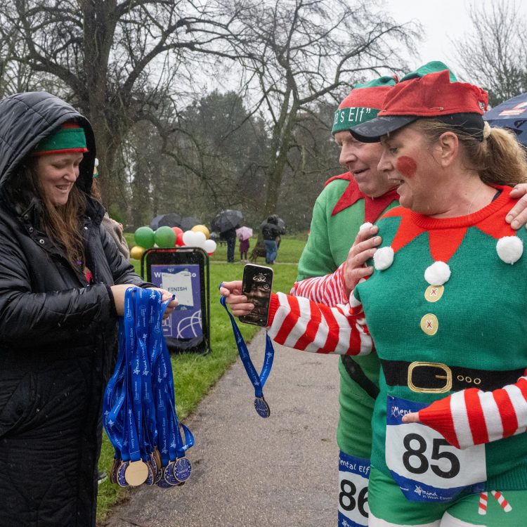 Two runners in elf outfits receive medals at the finish line