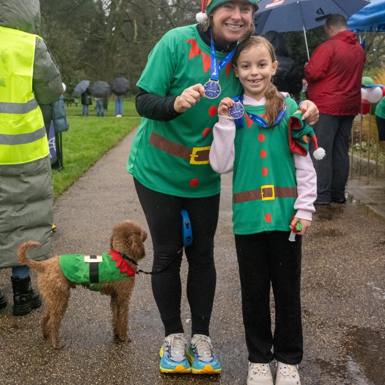A woman and girl pose with their medals alongside their dog