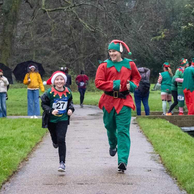 A man and boy in elf-themed outfits running towards the camera