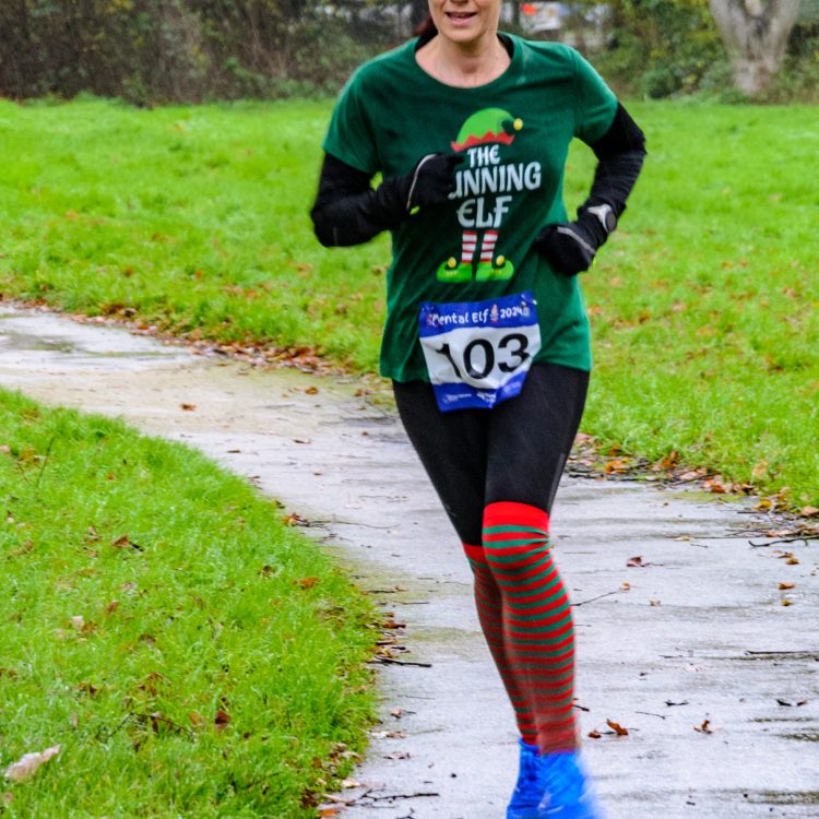 Woman dressed as an elf and Santa hat running