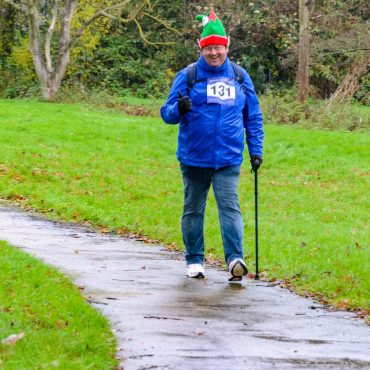 Man walking with a cane and elf hat